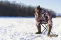 Bearded european man is boring while he fishing from ice hole