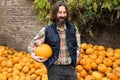 Bearded farmer with pumpkin on a background of a pile of pumpkins