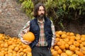 Bearded farmer with pumpkin on a background of a pile of pumpkins