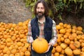 Bearded farmer with pumpkin on a background of a pile of pumpkins