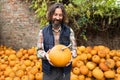 Bearded farmer with pumpkin on a background of a pile of pumpkins