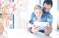 Bearded father with his young son using tablet PC in sunny room.Dad and little boy playing together on mobile computer Royalty Free Stock Photo