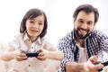 Bearded father with son plays computer game using game controllers. Royalty Free Stock Photo