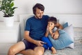 bearded father and son are sitting on the bed in T-shirts and watching football match on TV. a man holds a remote Royalty Free Stock Photo