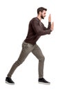 A bearded fit man in casual pants presses his hands over an invisible object in order to move it.