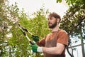bearded gardener in linen apron cutting