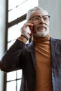 Bearded grey-haired man owning interior company calling client