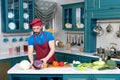 Bearded guy Cook in apron and cap. Chef cutting red cabbage for dinner