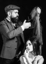 Bearded Hairdresser make fashion hairstail. Beautiful model with very long hair. Hairdresser, beauty salon.
