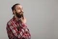 Bearded handsome man is thinking in red squared shirt on grey ba Royalty Free Stock Photo