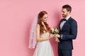 Bearded handsome man in tux with bow putting ring on finger of her girlfriedn in wedding dress Royalty Free Stock Photo