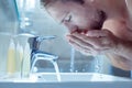 Bearded handsome man washing his face in the morning in light bathroom