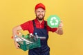 Bearded handyman standing and holding recycling sign and box with plastic bottles. Royalty Free Stock Photo