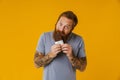 Bearded happy man eating chocolate bar while standing isolated