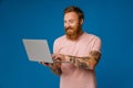 Bearded happy man holding laptop while standing isolated