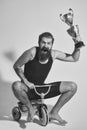 Bearded happy man holds gold champion cup on bicycle toy Royalty Free Stock Photo