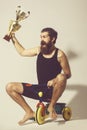 Bearded happy man holds gold champion cup on bicycle toy Royalty Free Stock Photo