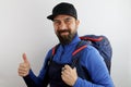 Bearded hiker with backpack and hat, success sign doing positive gesture with hand, thumbs up similing and happy.