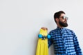 Bearded hipster in checkered shirt holding yellow skateboard