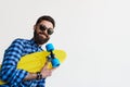 Bearded hipster in checkered shirt holding yellow skateboard