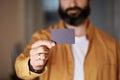 Bearded hipster holding hand empty black business card on blurred background. Mockup Copy Paste Blank Advertisement. Royalty Free Stock Photo