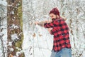 Bearded hipster man chopping wood in winter forest. Lumberjack in the snowy winter woodland. Bearded guy with axe outdoors