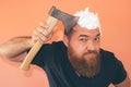 Bearded hipster man shaving his head with an axe Royalty Free Stock Photo