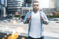 Bearded hipster man in sunglasses dressed in white t-shirt,denim shirt,stands on city street.Mock up.Space for logo,text Royalty Free Stock Photo