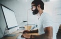 Bearded hipster professional wearing eye glasses working at modern loft studio-office with desktop computer.White blank Royalty Free Stock Photo