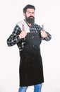 Bearded hipster wear apron for barbecue. Roasting and grilling food. Man hold cooking utensils barbecue. Tools for Royalty Free Stock Photo