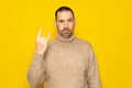 Bearded hispanic man in his 40s wearing a beige turtleneck making the rock gesture while looking at the camera very Royalty Free Stock Photo