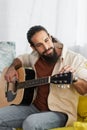 bearded hispanic musician tunning acoustic guitar