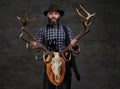 Bearded hunter in a fleece shirt and hat holds his trophy.