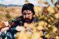 Bearded hunter man holding gun and walking in forest. Hunter with shotgun gun on hunt. Close up Portrait of hamdsome