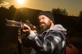 Bearded hunter man holding gun and walking in forest. Rifle Hunter Silhouetted in Beautiful Sunset. Autunm hunting