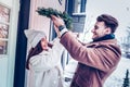 Bearded husband putting Christmas wreath oh head of his wife