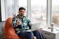 Bearded indian man showing thumb up with laptop on knees Royalty Free Stock Photo