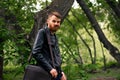 A bearded Irishman in a leather jacket makes faces in the middle of the forest