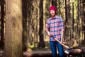 Bearded logger in a checkered shirt with an ax standing near a t