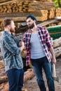 bearded lumberjack in checkered shirt holding axe and shaking hands with partner