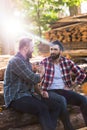 bearded lumberjacks shaking hands of each other and sitting on logs