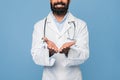 Bearded male medical doctor wearing white medical coat with a stethoscope, holding something invisible in his palms