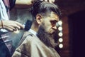 Bearded male sitting in barber shop while hairdresser shaves his beard. Bearded man getting powder on skin with makeup Royalty Free Stock Photo