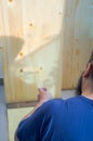 Bearded man applying clear coat paint on a wooden surface with roller brush. Painting wood wall and floor Royalty Free Stock Photo