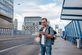 Bearded man with ball under arm using phone while waiting for bus. Royalty Free Stock Photo
