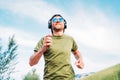 Bearded man in baseball cap, wireless headphones and blue sunglasses cheerful smiling running evening run and holding in hand