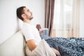 Bearded man in bed drinking morning coffee in sunrise light at home Royalty Free Stock Photo