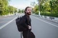 Bearded man in black clothes jaywalking. Dangerous crossing the road