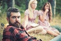 Bearded man with blue eyes spending time with friends outdoors. Closeup handsome man in lumberjack shirt lying on glass