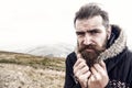 Bearded man, brutal caucasian hipster with moustache cold on mountain